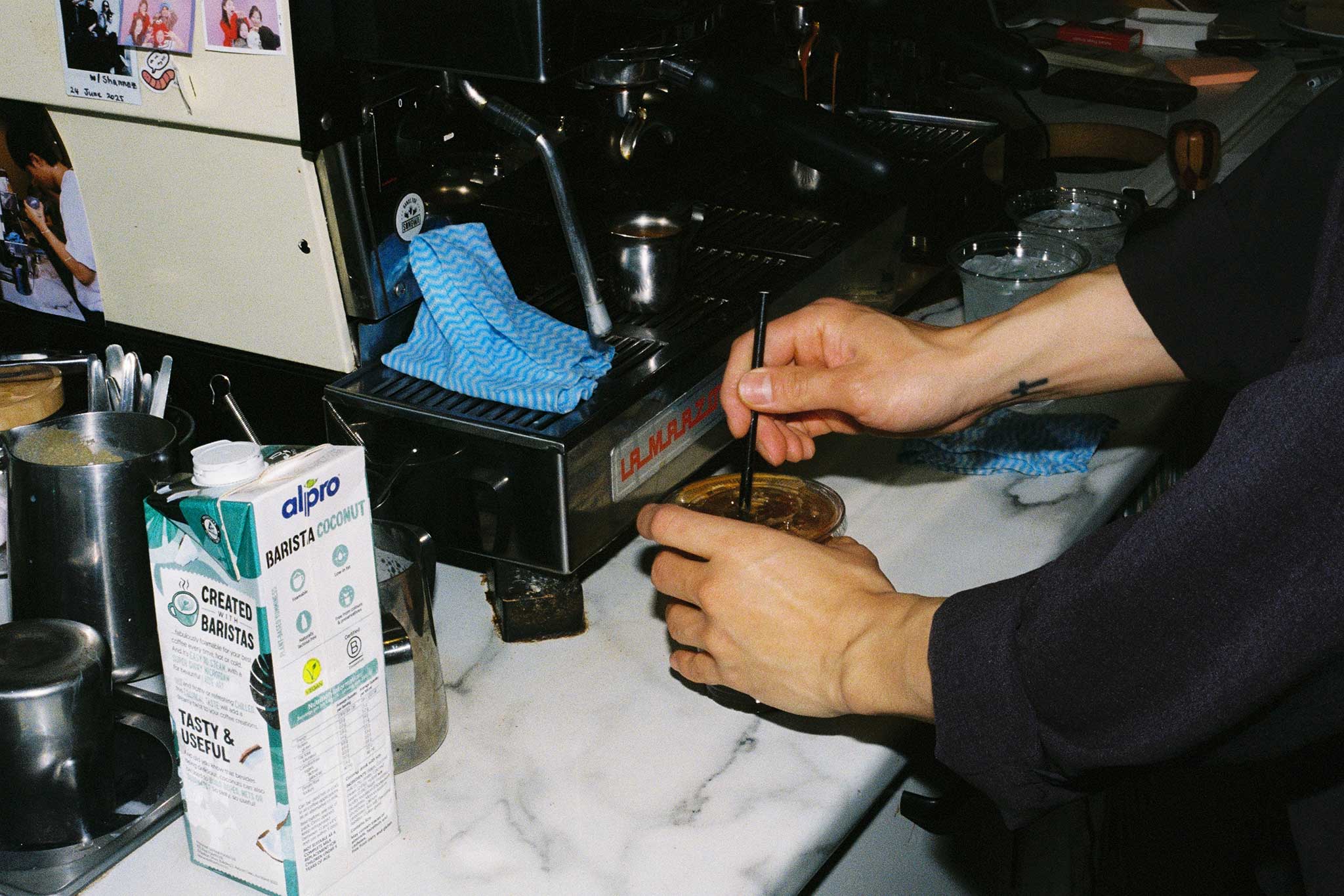 Barista behind the bar making iced coffee. 35mm aesthetic brand social media imagery for cafés and restaurants.