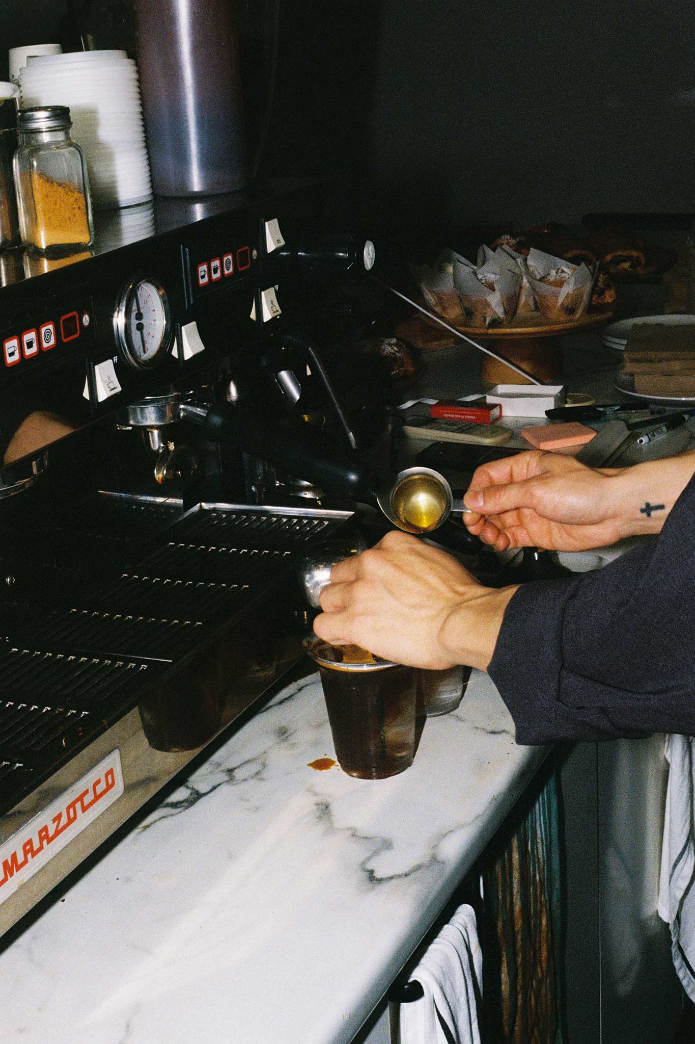 Barista behind the bar making iced coffees. 35mm aesthetic brand social media imagery for cafés and restaurants.